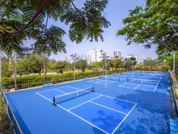 Dãy sân pickleball ngoài trời mặt xanh dương, có hàng cây bao quanh, ở Ariyana Pickleball Centre, Đà Nẵng
